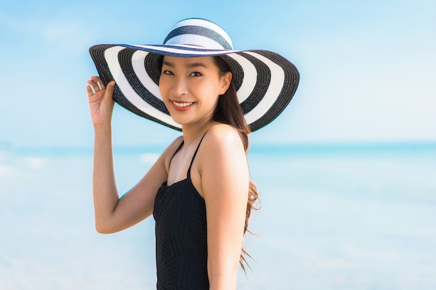 Mujer asiática joven hermosa del retrato feliz y sonrisa en la playa y el mar