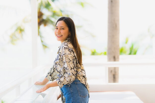 Mujer asiática joven hermosa del retrato feliz y sonrisa con viaje en el mar y la playa neary del centro turístico del hotel