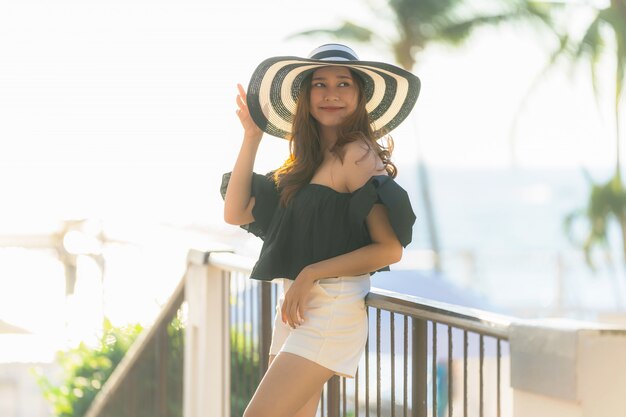 Mujer asiática joven hermosa del retrato feliz y sonrisa con viaje en el mar y la playa neary del centro turístico del hotel