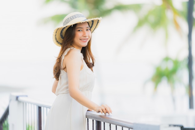 Mujer asiática joven hermosa del retrato feliz y sonrisa con viaje en el mar y la playa neary del centro turístico del hotel