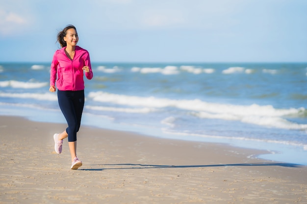 Mujer asiática joven hermosa del retrato que corre o ejercita en el paisaje de la naturaleza del tropica de la playa