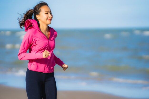 Mujer asiática joven hermosa del retrato que corre o ejercita en el paisaje de la naturaleza del tropica de la playa