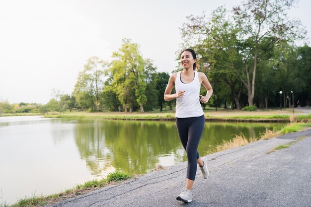 Mujer asiática joven hermosa sana del corredor en la ropa de los deportes que corre y que activa