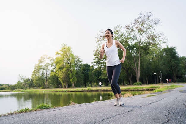 Mujer asiática joven hermosa sana del corredor en la ropa de los deportes que corre y que activa