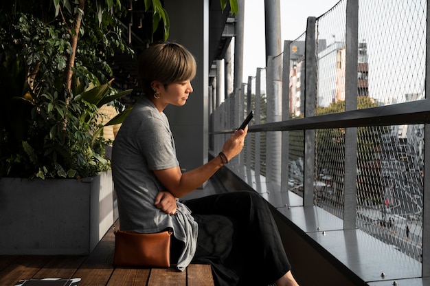 Foto gratuita mujer asiática joven que controla su smartphone al aire libre