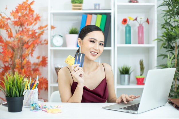 Mujer asiática joven que paga con la tarjeta de crédito