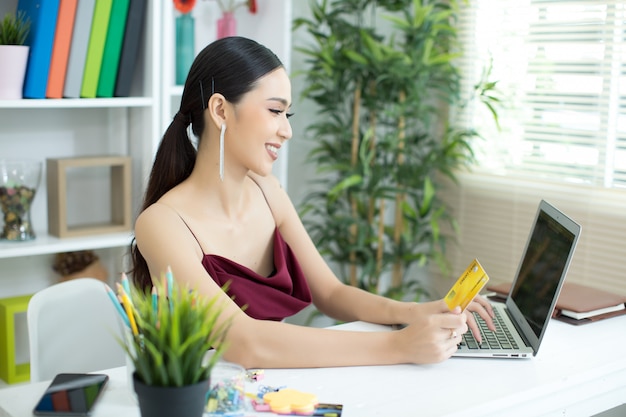 Mujer asiática joven que paga con la tarjeta de crédito