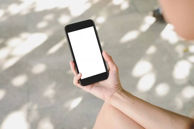 Mujer asiática joven que usa el teléfono inteligente mock up pantalla en blanco en blanco en café