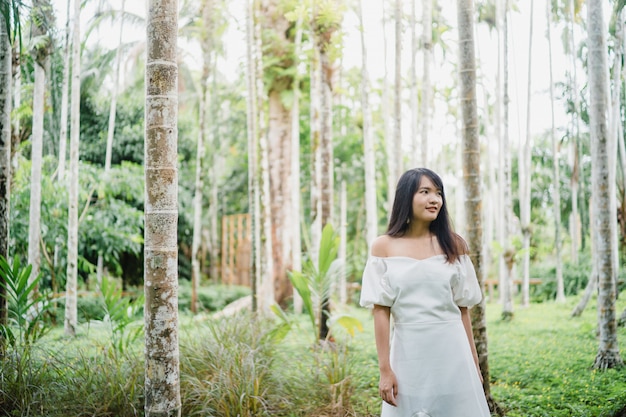 La mujer asiática joven se relaja en el bosque, el utilizar femenino hermoso feliz relaja tiempo en naturaleza.