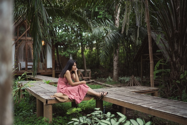 La mujer asiática joven se relaja en el bosque, el utilizar femenino hermoso feliz relaja tiempo en naturaleza.