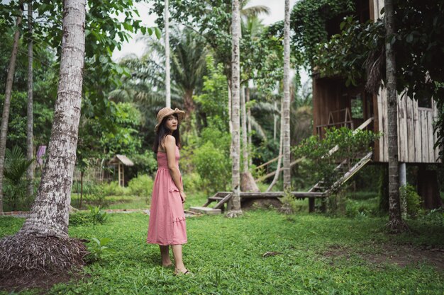 La mujer asiática joven se relaja en el bosque, el utilizar femenino hermoso feliz relaja tiempo en naturaleza.