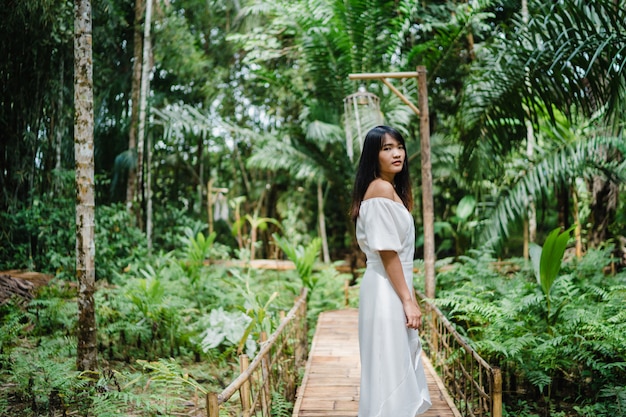 La mujer asiática joven se relaja en el bosque, el utilizar femenino hermoso feliz relaja tiempo en naturaleza.