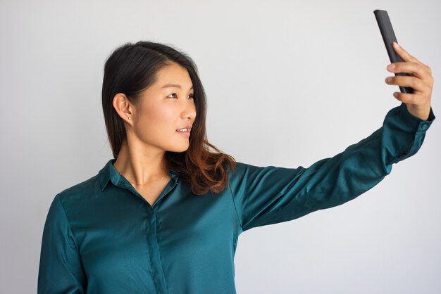 Mujer asiática joven en ropa de sport que toma el selfie con el teléfono.