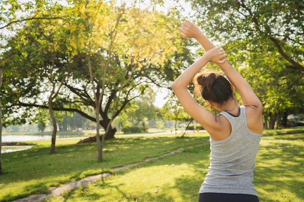 La mujer asiática joven sana del corredor calienta el cuerpo que estira antes de ejercicio y de yoga