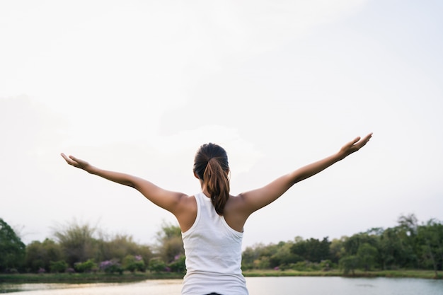 La mujer asiática joven sana del corredor calienta el cuerpo que estira antes de ejercicio y de yoga