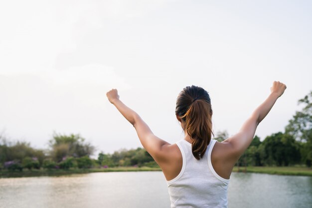 La mujer asiática joven sana del corredor calienta el cuerpo que estira antes de ejercicio y de yoga