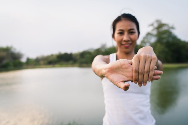 La mujer asiática joven sana del corredor calienta el cuerpo que estira antes de ejercicio y de yoga