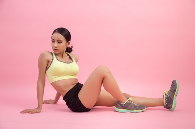 Mujer asiática joven sana hermosa que hace un ejercicio que estira antes de jugar un deporte.