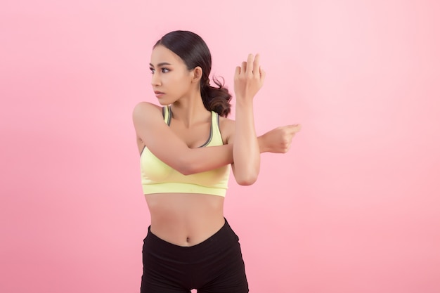 Mujer asiática joven sana hermosa que hace un ejercicio que estira antes de jugar un deporte.