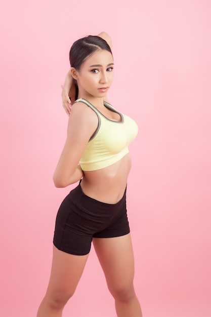 Mujer asiática joven sana hermosa que hace un ejercicio que estira antes de jugar un deporte.
