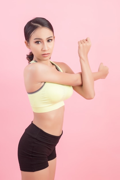 Mujer asiática joven sana hermosa que hace un ejercicio que estira antes de jugar un deporte.