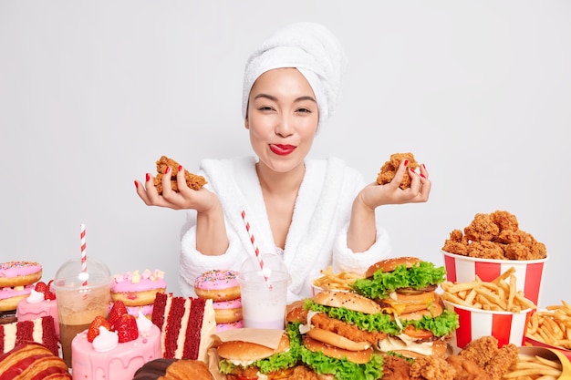 Mujer asiática joven satisfecha con manicura de lápiz labial rojo tiene deliciosas pepitas adicto a la comida rápida