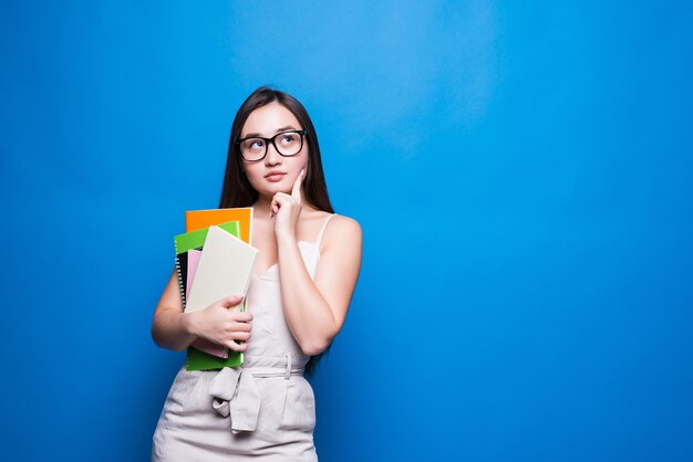 La mujer asiática joven sonríe y tiene libros en sus manos. Concepto de educación, colegio, sesión, examen.