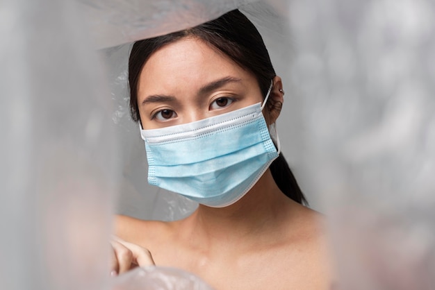 Mujer asiática con máscara médica está cubierta de plástico