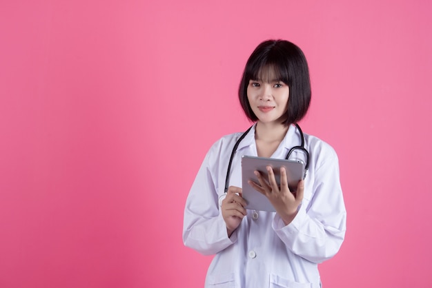 Mujer asiática médico con bata blanca sobre rosa