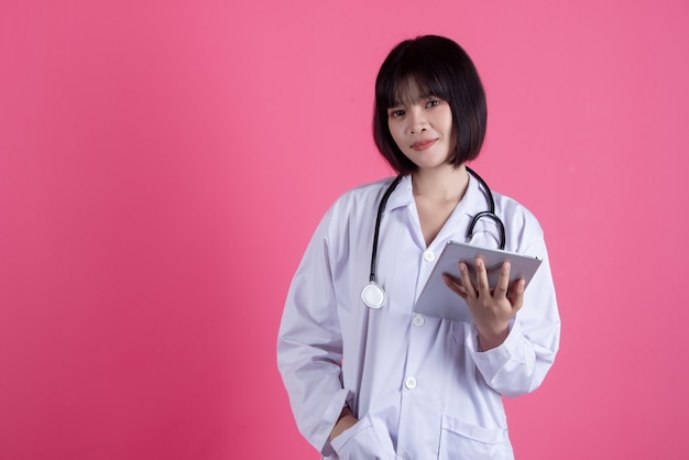 Mujer asiática médico con bata blanca sobre rosa