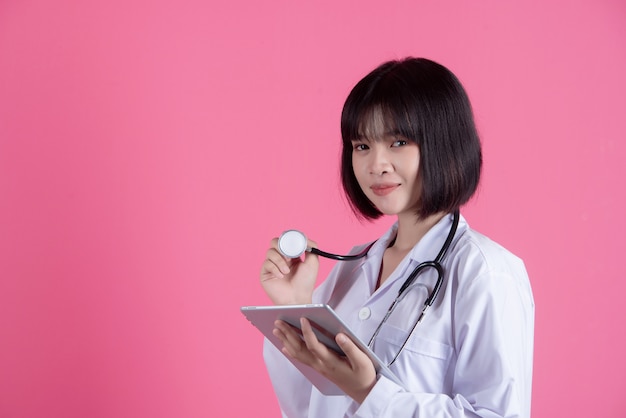 Mujer asiática médico con bata blanca sobre rosa