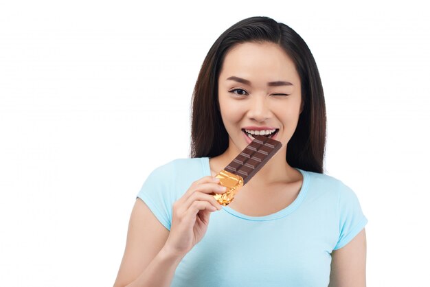 Mujer asiática mordiendo barra de chocolate