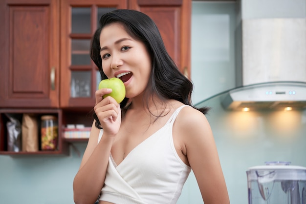 Mujer asiática mordiendo manzana verde