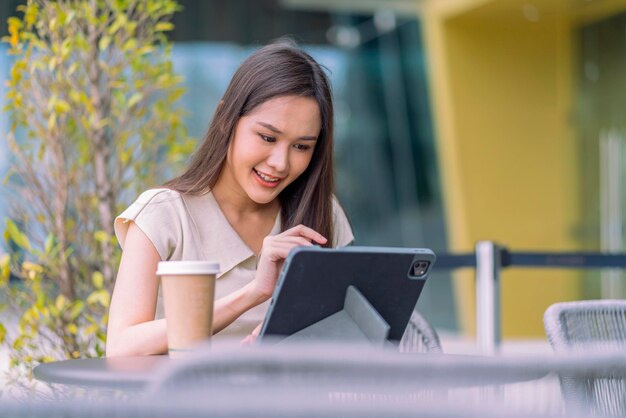 Mujer asiática nómada digital felicidad libertad alegre sonriente trabajando usando tableta en el jardín al aire libreasia mujer independiente relajarse ocio trabajando en cualquier lugar trabajar y viajar con fondo de jardín bokeh