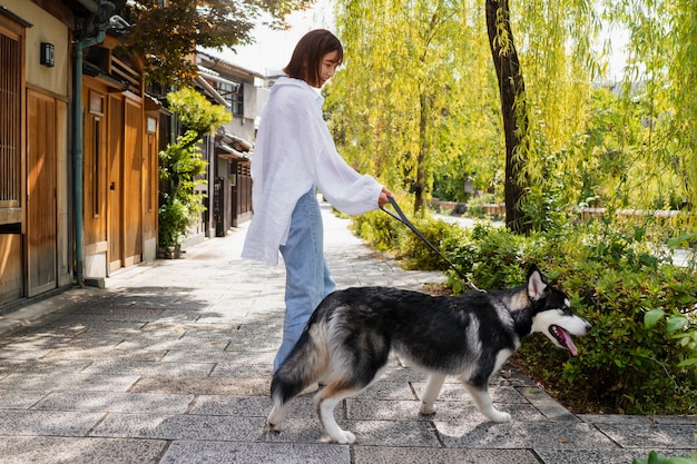 Foto gratuita mujer asiática paseando a su perro husky al aire libre