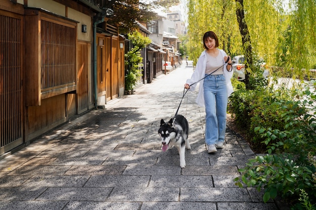 Mujer asiática paseando a su perro husky al aire libre