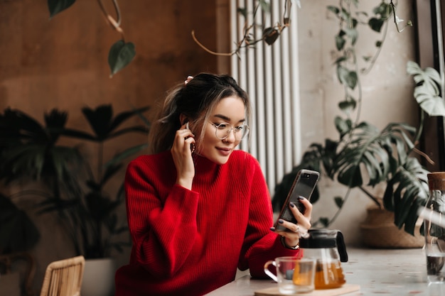 Mujer asiática se pone el auricular inalámbrico y sostiene el teléfono inteligente