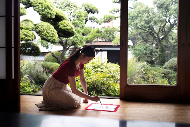 Mujer asiática practicando escritura japonesa en interiores