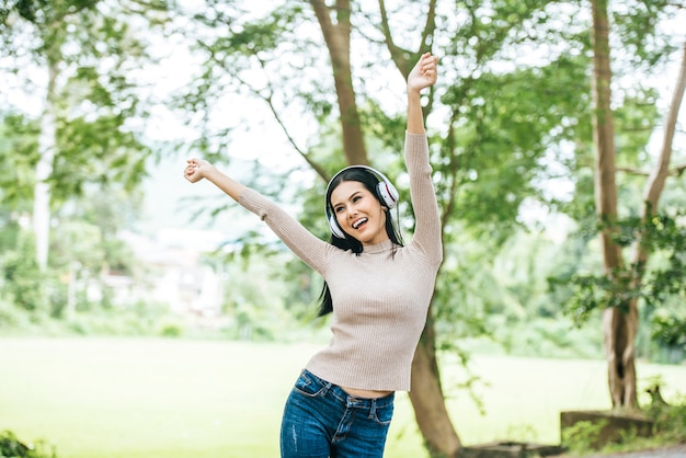 Mujer asiática que escucha la música preferida en los auriculares. Tiempo feliz y relajarse