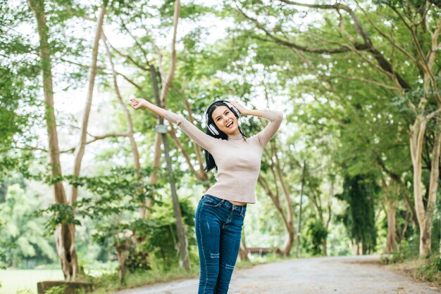 Mujer asiática que escucha la música preferida en los auriculares. Tiempo feliz y relajarse