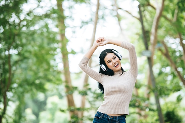 Mujer asiática que escucha la música preferida en los auriculares. Tiempo feliz y relajarse