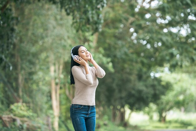 Mujer asiática que escucha la música preferida en los auriculares. Tiempo feliz y relajarse