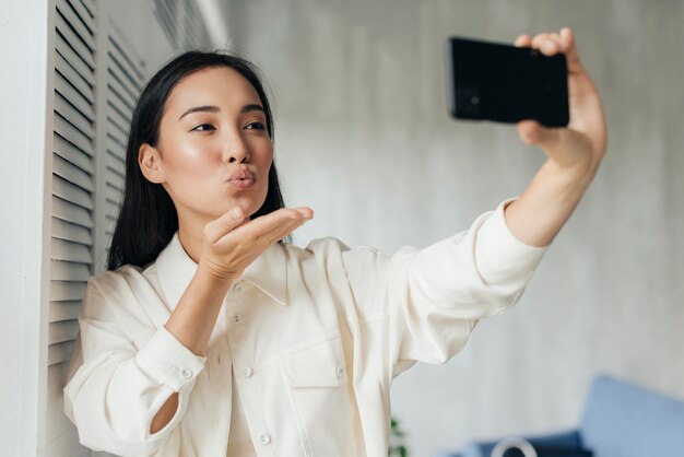 Mujer asiática que sopla un beso a sus seguidores