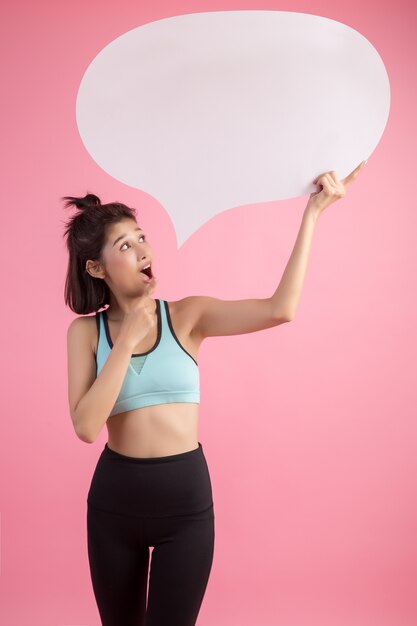 Mujer asiática que sostiene y que mira para arriba a la burbuja del discurso con el espacio vacío para el texto en rosa