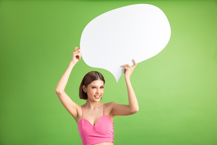 Foto gratuito mujer asiática que sostiene y que mira para arriba a la burbuja del discurso con el espacio vacío para el texto en verde