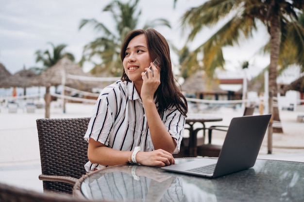Mujer asiática que trabaja en la computadora portátil en vacaciones