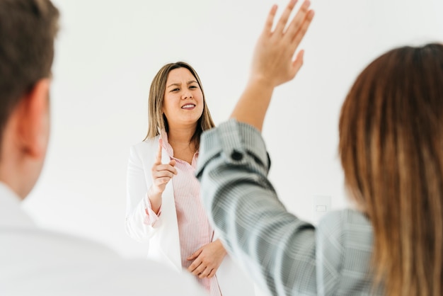 Mujer asiática respondiendo preguntas de compañeros de trabajo