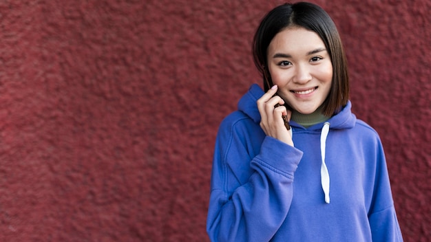 Mujer asiática sonriente hablando por teléfono