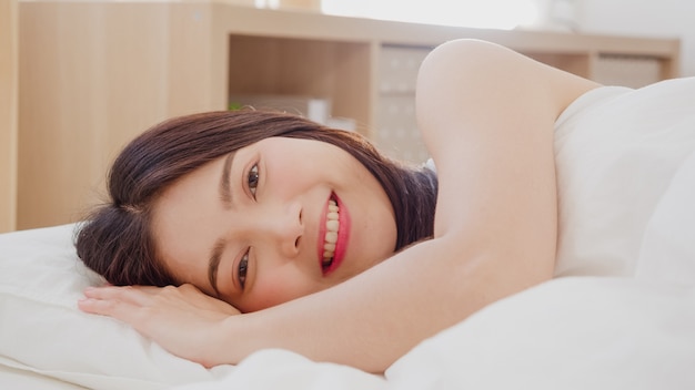 Mujer asiática, sonriente, mentira en cama, en, dormitorio