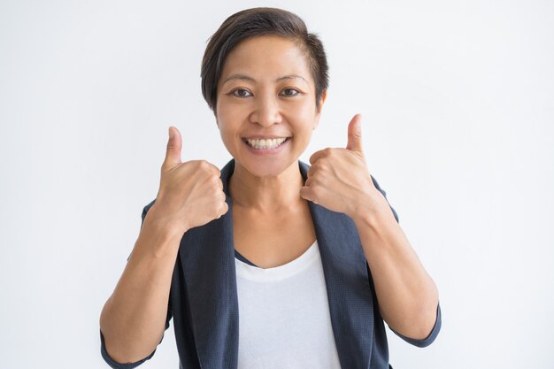 Mujer asiática sonriente que muestra ambos pulgares para arriba